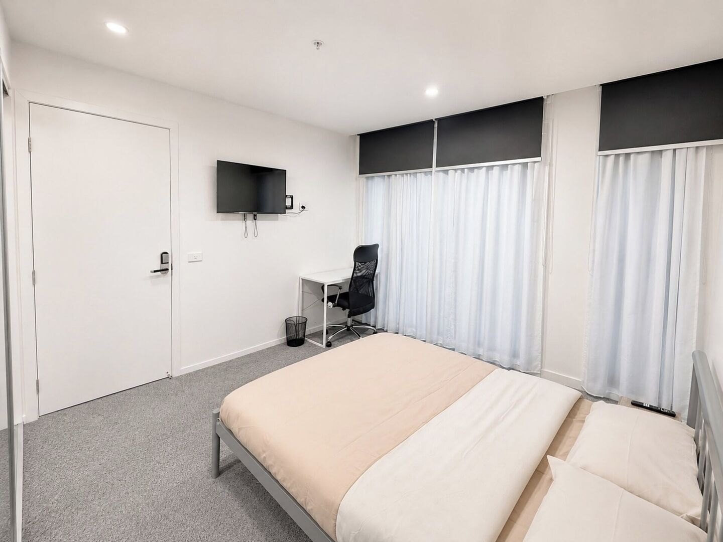 Hotelkamer met een bed, bureau, stoel, televisie en een raam met gordijnen.