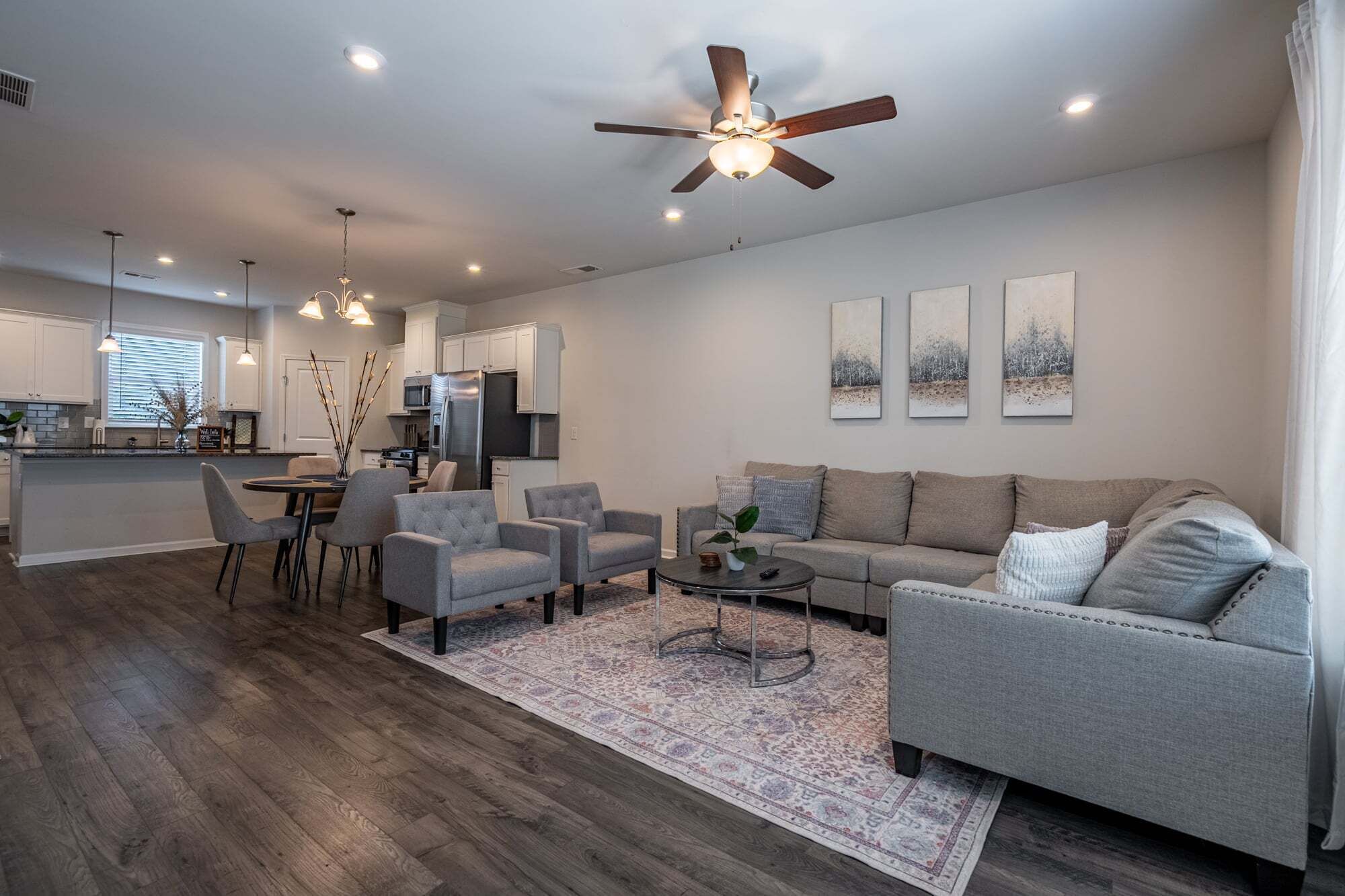 A modern living room with a grey sofa, two armchairs, a coffee table, and a patterned rug.
