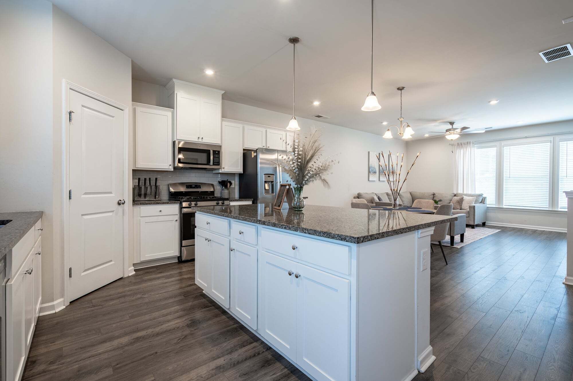 A modern kitchen with white cabinetry, a central island, and pendant lighting.