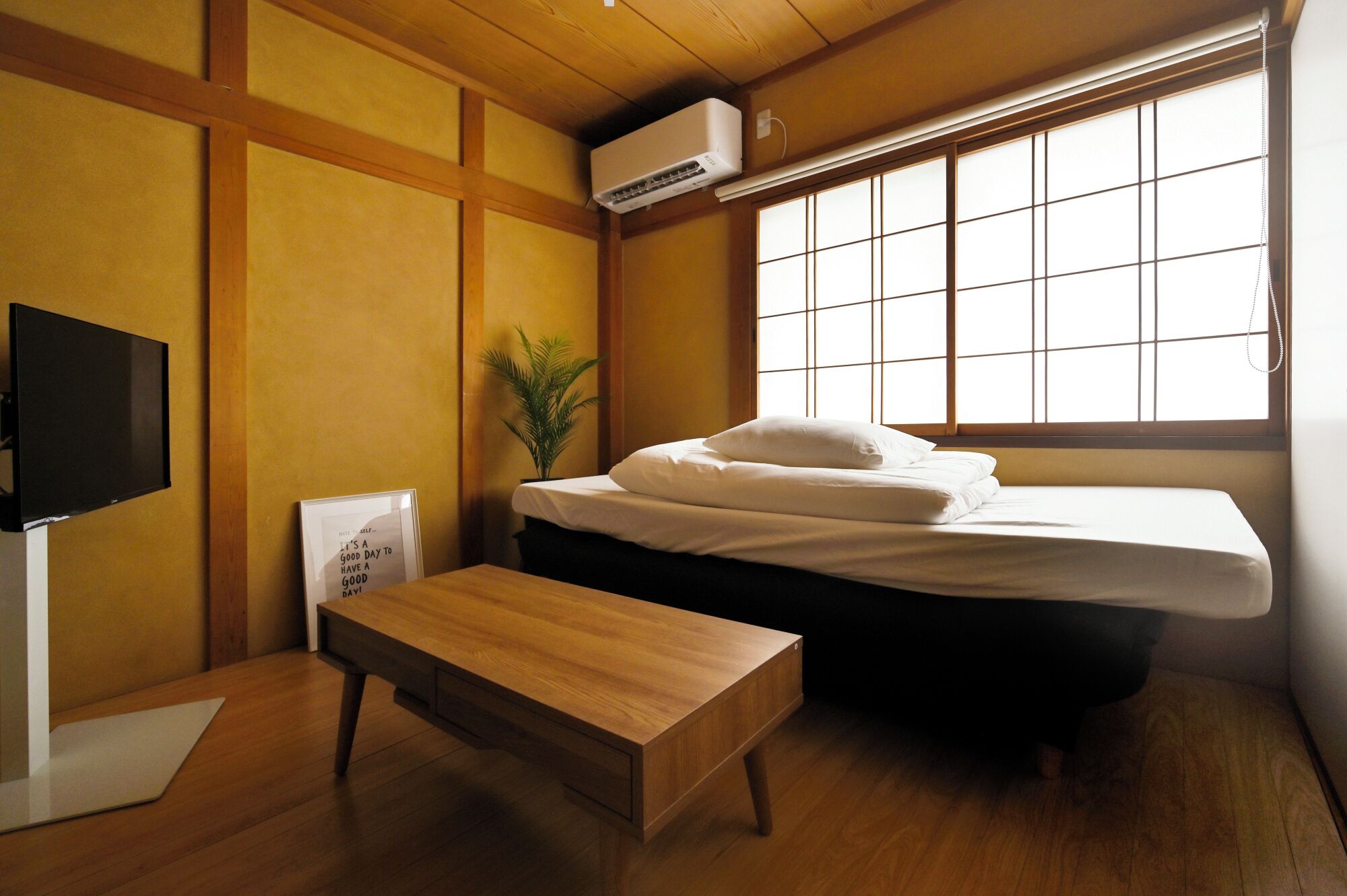 A room with a bed, a desk, a television, and a large window.