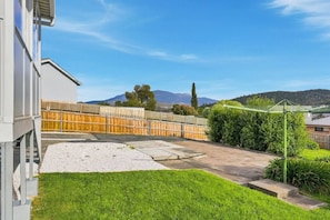 Ein Wohngrundstück mit Holzfence, einem Rasen und freiem Blick auf ein Gebirge im Hintergrund.