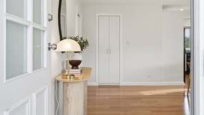 Ein Flur mit Holzboden, einer weißen Tür und einer Lampe auf einer Holzkonsole.