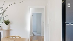 Eine moderne Küche mit einem schwarzen Kühlschrank, einem Esstisch mit Stühlen und einem Gang zu einem anderen Raum.