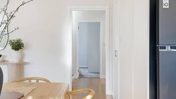 A modern kitchen with a black refrigerator, a dining table with chairs, and a hallway leading to another room.