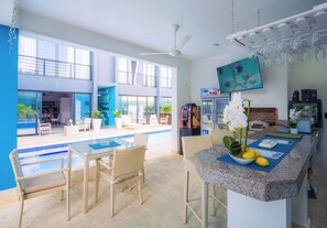Une cuisine moderne avec des comptoirs en granit, un coin repas avec des chaises en osier et une vue sur une piscine et un espace de détente extérieur.