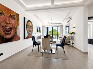 A modern interior with a dining area, large windows, and artwork on the walls. - Stylish 1-Bed – LAP Pool - Wi-Fi - GYM - Hot water (Sosúa)