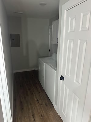 A laundry room with a white door, a washing machine, and a dryer. - The Phoggy Cottage (Lawrence)