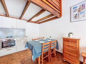 A compact kitchen with a built-in oven, a dining table set for four, and a wooden cabinet. - Les Maisons de l'Océan by Interhome (Les Mathes)
