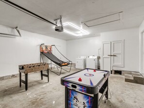 Une pièce équipée d’un baby-foot, d’une table de billard et d’un petit panier de basket.