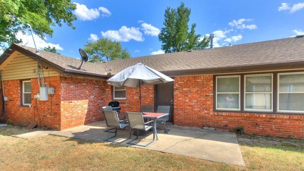 A brick house with a patio, a table, and two chairs. - Modern Cozy OKC Stay Near Fairgrounds (Oklahoma City)