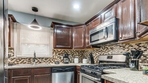 A kitchen with wooden cabinets, a stainless steel microwave, a dishwasher, and a gas stove. - Modern Cozy OKC Stay Near Fairgrounds (Oklahoma City)