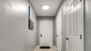 A hallway with a white door, a doormat, and a framed picture on the wall. - Modern Cozy OKC Stay Near Fairgrounds (Oklahoma City)