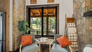 A cozy room with a stone wall, a wooden ceiling, a large window with a view of trees, a fireplace, and a Samsung refrigerator. - Legacy Springs at Eagles Nest - hot tub, creek (Banner Elk)