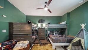 A bedroom with bunk beds, a desk, a chair, a bed with a patterned bedspread, a small tent, and a ceiling fan. - Legacy Springs at Eagles Nest - hot tub, creek (Banner Elk)