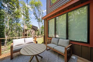 Una terraza de madera con una mesa redonda y dos sofás con cojines.