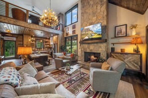 A spacious living area with a fireplace, comfortable seating, and a large TV mounted above it. - Legacy Springs at Eagles Nest - hot tub, creek (Banner Elk)