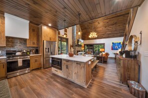 A modern kitchen with wooden cabinets, stainless steel appliances, and a large island. - Legacy Springs at Eagles Nest - hot tub, creek (Banner Elk)