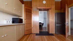 A kitchen with wooden cabinets, a microwave, a refrigerator, and a door leading to another room. - Lovely Family Home in South Launceston - Prime Location (South Launceston)