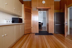 Eine Küche mit Holzausstattung, einer Mikrowelle, einem Kühlschrank und einer Tür zu einem anderen Raum.