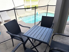 Ett område vid poolen med ett bord och stolar, en pool och utsikt över omgivningen.