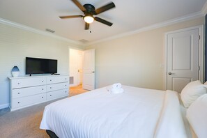 A bedroom with a bed, a dresser, a television, and a ceiling fan. - Sweet Home Near Disney —5BR Resort Villa + Private Pool (Kissimmee)
