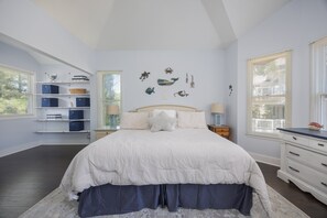 A bedroom with a bed, a nightstand, a dresser, a window, and a wall with decorative items. - 1062 - Beach House Blessings Spacious 5BR Corolla retreat with private pool, deck, and elevator. (Corolla)