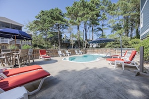 A pool area with lounge chairs and umbrellas, surrounded by trees and a wooden fence. - 1062 - Beach House Blessings Spacious 5BR Corolla retreat with private pool, deck, and elevator. (Corolla)
