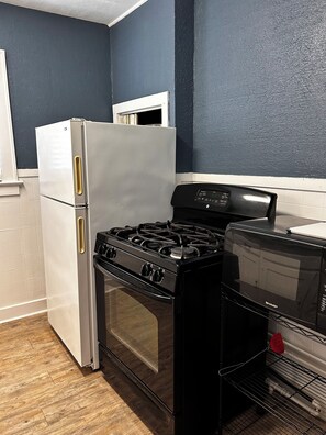 Una cocina con un refrigerador blanco, una estufa negra y un microondas.