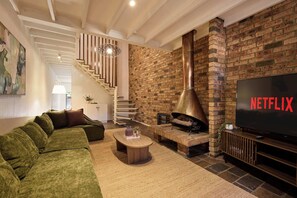 A modern living room with a sectional sofa, a fireplace, a TV, and a staircase. - 3BR Glebe House | Garage Parking, Near Fish Market (Glebe)