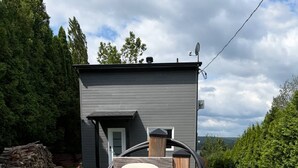 Una estación de carga para vehículos eléctricos con una caja blanca que dice 'Atti Home' frente a una casa.