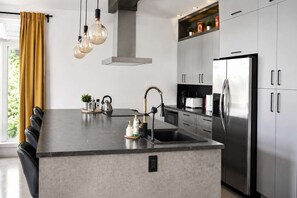 Una cocina moderna con una isla central, electrodomésticos de acero inoxidable y encimera negra.