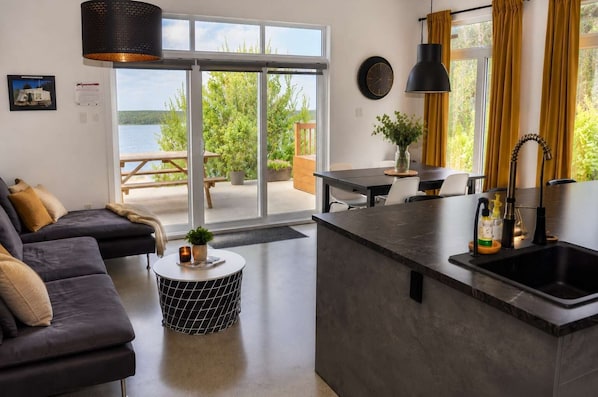 A modern living room with a sofa, a round coffee table, and a kitchen area with a sink and countertop.