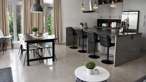 Una cocina moderna con una isla central, taburetes de bar y un comedor con mesa y sillas.