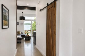 Un pasillo con una puerta corredera estilo granero, un sofá, una mesa de centro redonda y vistas a un lago a través de una puerta de cristal.