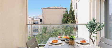 A balcony with a table set for two, overlooking a cityscape.