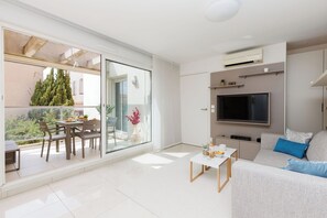 Ein modernes Wohnzimmer mit einer Couch, einem Fernseher und einem Essbereich mit Tisch und Stühlen.