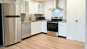 Une cuisine moderne dotée d’appareils électroménagers en acier inoxydable, de meubles blancs et d’un plancher en bois.