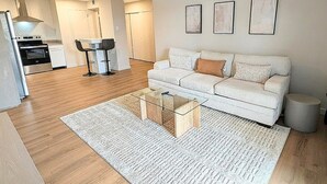 Un salon moderne avec un canapé, une table basse et un coin cuisine à l’arrière-plan.