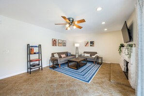 A living room with a ceiling fan, two sofas, a coffee table, a floor lamp, and a fireplace. - Newell's Nest, Large Pool, Games BBQ Island, 3 bedroom, Outdoor Seating, Parking (Riverside)