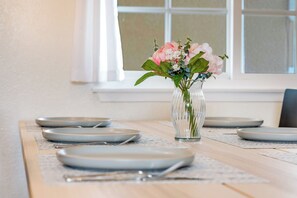 A dining table with plates and cutlery, a vase with flowers, and a window in the background. - Newell's Nest, Large Pool, Games BBQ Island, 3 bedroom, Outdoor Seating, Parking (Riverside)