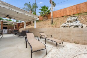 An outdoor patio with a grill, seating area, and a wooden fence. - Newell's Nest, Large Pool, Games BBQ Island, 3 bedroom, Outdoor Seating, Parking (Riverside)