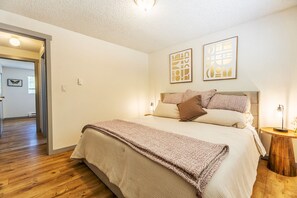Ein Schlafzimmer mit einem Bett, einem Nachttisch und zwei Wandbildern.