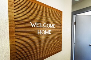 Eine Holzpaneele verkleidete Wand mit der Aufschrift "WELCOME HOME" in weißen Buchstaben.