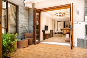 Una terraza de madera que conduce a un interior moderno con comedor y cocina.
