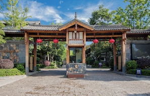 A traditional wooden pavilion with a tiled roof, surrounded by greenery and stone walls. - Lijiang Yueyun Boutique Hotel (Lijiang)