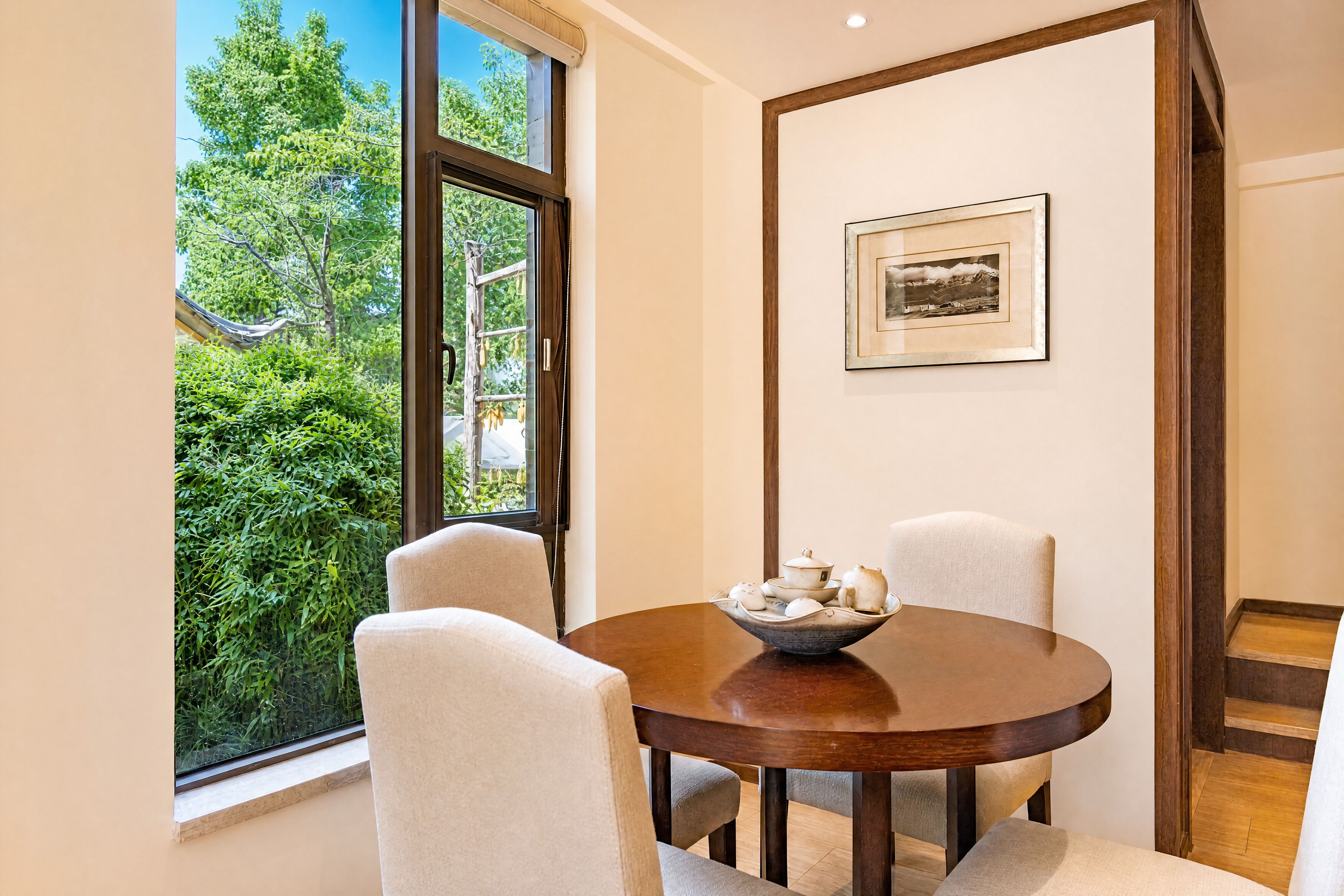 A dining area with a round table, chairs, and a bowl of teapots.