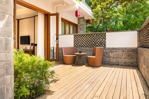 Eine Holzterrasse mit Korbmöbeln und einer Steinmauer.