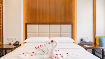 Habitación de hotel con cama, cabecera de madera, mesita de noche con teléfono y en la pared un enchufe.