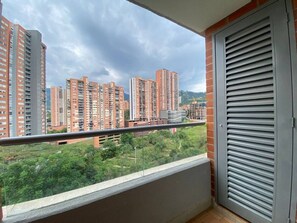 Un balcón con vistas a edificios altos y zonas verdes.