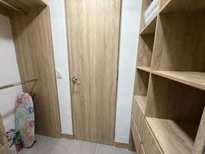 A wooden wardrobe with a door, a shelf unit, and a patterned ironing board. - In Sabaneta | Apartment | Security | Extra Services | Parking | Overlooking a Nature Reserve (Sabaneta)